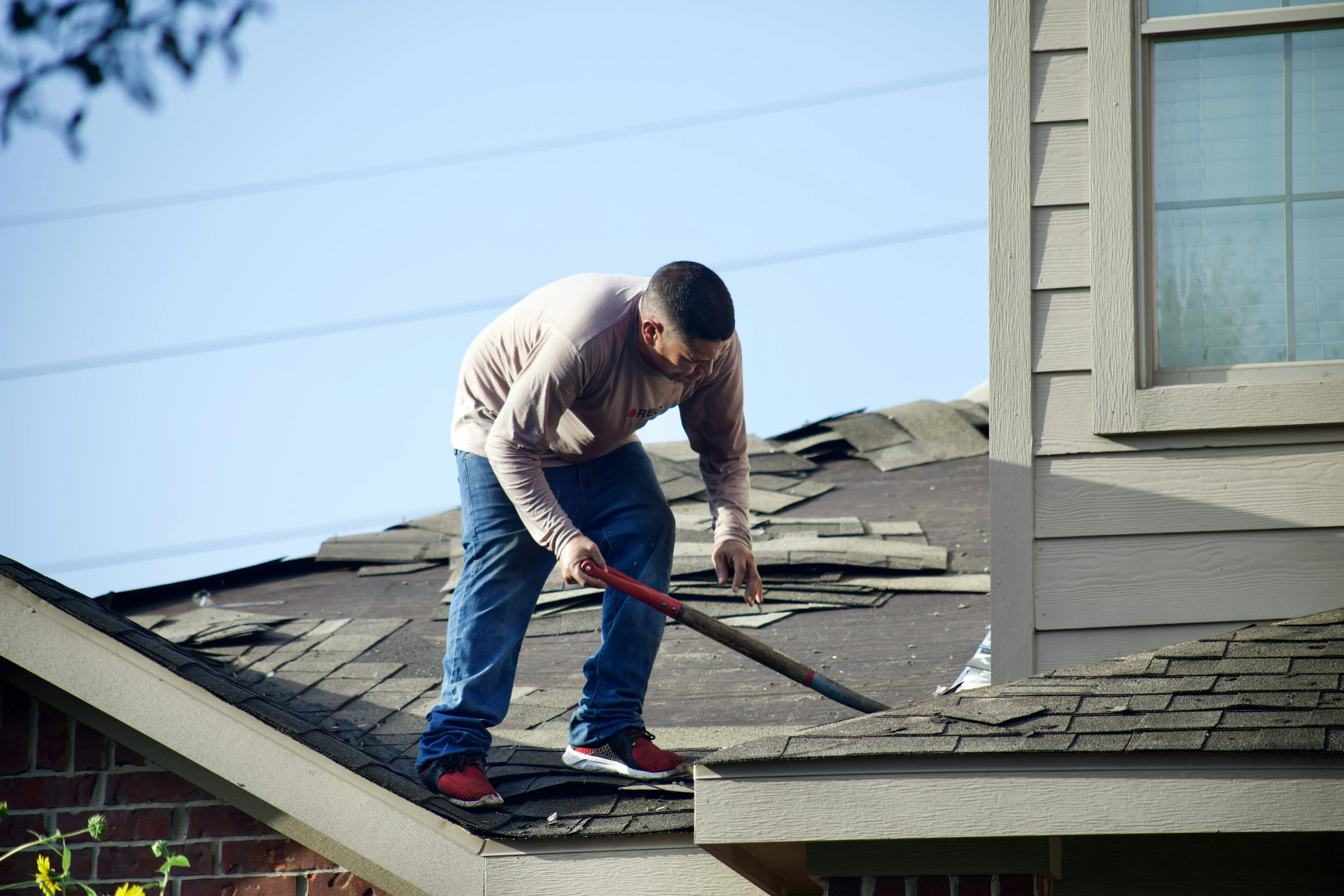 Man pulling tiles on roof.